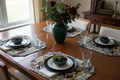 Set of 4 tropical floral quilted placemats arranged on a dining room table with place settings in an elegant home setting